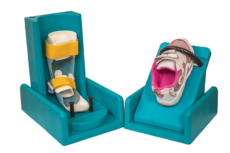 The blue Original AFO Assist cradle and show platform are displays with a child-sized AFO and sneaker.