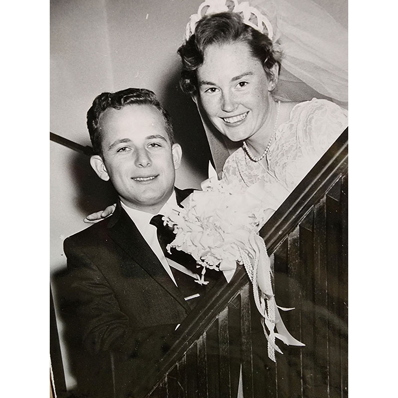 Black and white photo of a young 50s era couple smiling on their wedding day.